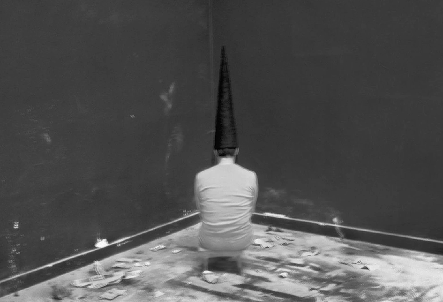 Mujer con capirote sentada de cara a la pared